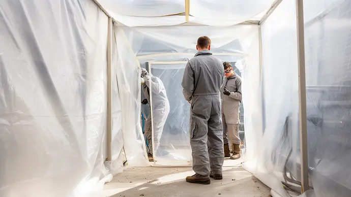 Gecertificeerd saneringsteam werkt in een afgeschermde asbestzone